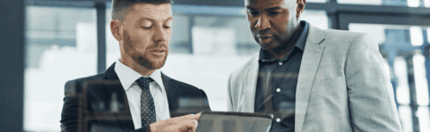 two businessmen reviewing a file on a digital tablet in an office environment
