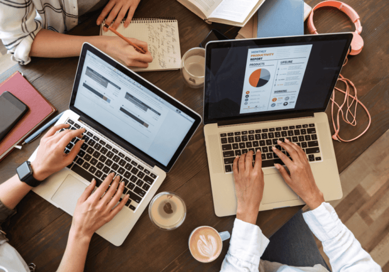 working on laptops two people working on laptop computers side-by-side