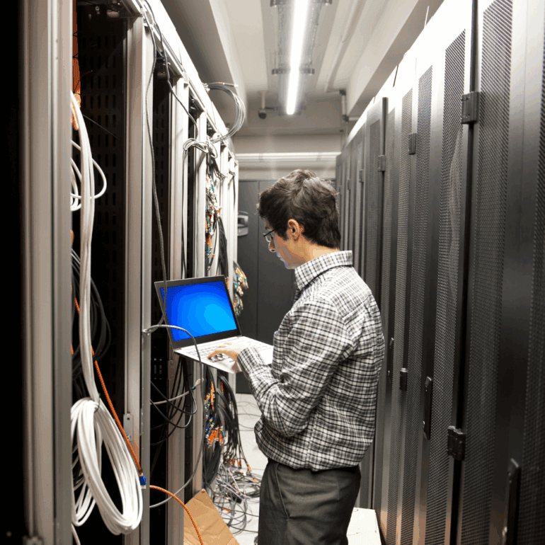 An IT technician programming computer equipment in a server room
