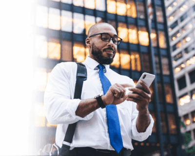  Office worker looking at a white smartphone with office buildings in the background